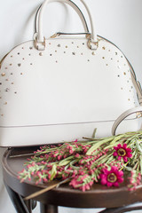 womens leather bag on a red leather sofa, leather white handbag (close up)