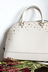 womens leather bag on a red leather sofa, leather white handbag (vertically, close up)
