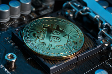 Golden Bitcoin Cryptocurrency on computer circuit board CPU. Macro shot.