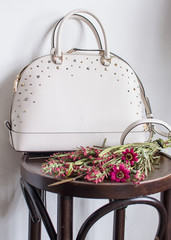 womens leather bag on a wooden table, leather white handbag (vertically)