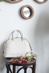 womens leather bag on a wooden table, leather white handbag, bag in the interior of the room