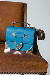 blue female clutch on a brown chair, clutch on the arm of the chair, small womens bag