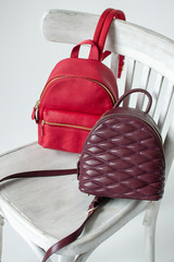 Burgundy and red leather backpacks on white wooden chair, womens leather backpacks