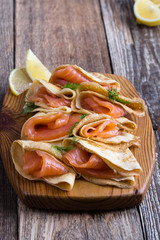 Smoked salmon appetizer, stuffed crepes on wooden board