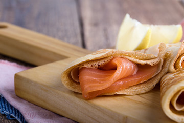 Smoked salmon appetizer, stuffed crepes on wooden board
