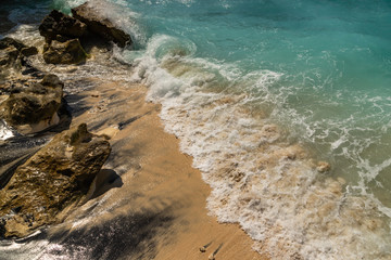 Atuh beach at Nusa penida island landscape famous for tourists. Waves crashing on sand and rocks.
