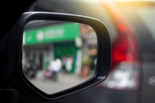 Car Mirror with blur image of green Shop.