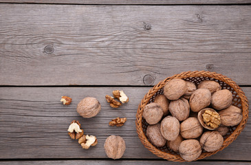 Walnuts kernels in basket on grey wooden background
