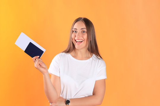 Excited young woman tourist standing isolated on yellow background holding passport with tickets looking camera.