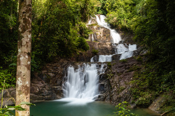 Fototapeta premium Long exposure of a beautiful waterfall running through tropical rainforest (Lampi, Thailand)