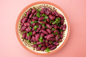 Cooked red beans plate on pink background, isolated. Healthy food.