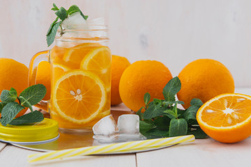 Photo orange juice and ice mint on a white wooden table.