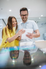 Man and woman looking for tablet to buy while standing in the store.