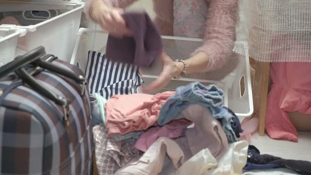A beautiful girl, a young mother picks up and folds children's clothes in baskets in her dressing room. puts things in order
