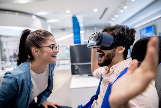 Surprised man wearing VR glasses and woman crouching in front of him.