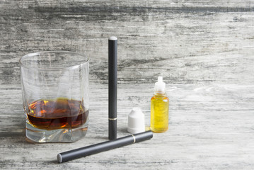 Not a full glass of alcoholic whiskey drink with an e-cigarette on a marble surface.Bad habits harmful to health 
