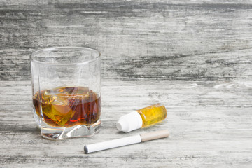 Not a full glass of alcoholic whiskey drink with an e-cigarette on a marble surface.Bad habits harmful to health