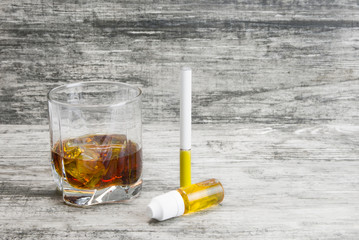 Not a full glass of alcoholic whiskey drink with an e-cigarette on a marble surface.Bad habits harmful to health 