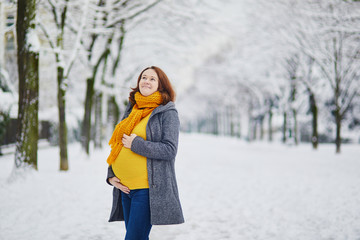 Beautiful pregnant woman walking in winter park