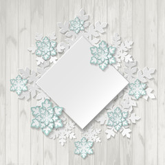 Paper snowflakes on wooden background with place for your text.
