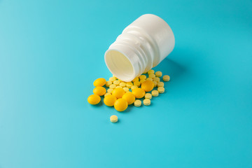 Yellow pills and plastic white bottle. Blue background with copy space for text