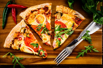 Pizza with pepper,ham and champignon on cutting board on wooden table