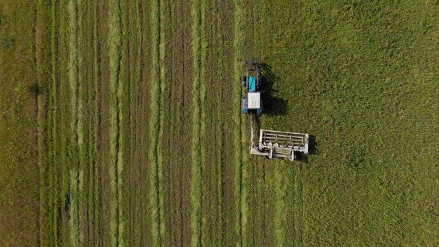 Aerial shot from top to down of tractor cutting grass and moving forward