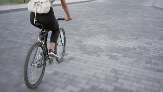 View of legs of beautiful young woman cycling on urban bike in city