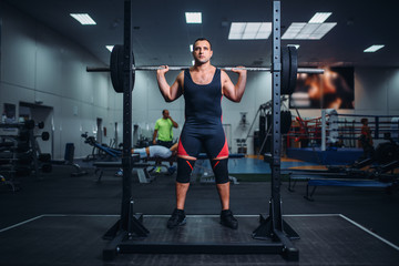 Obraz na płótnie Canvas Athlete prepares to make squats with barbell