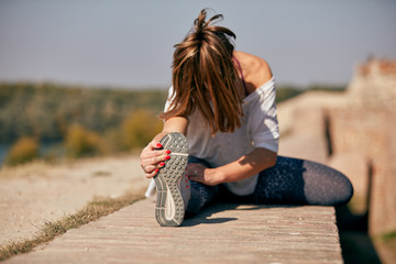 Portrait of sporty young woman doing stretching in city.