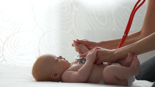 Kid doctor examing happy baby boy with stethoscope