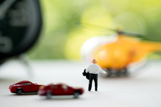 Rear view of miniature businessman walking towards helicopter.