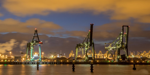 Fototapeta premium Industrial landscape with Harbor quay and loading cranes at night