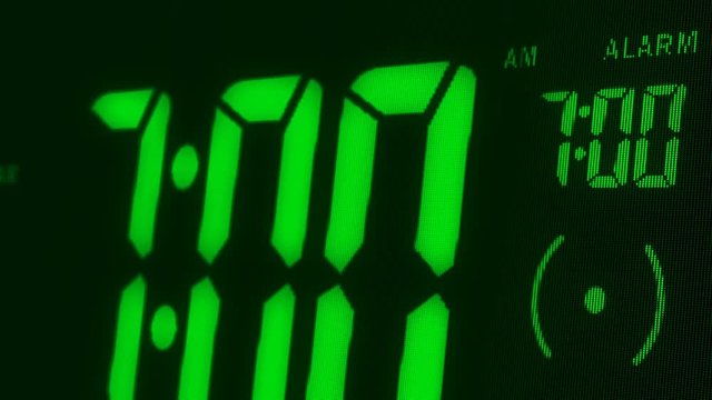 Digital alarm clock waking up at 7 AM. Close-up LED display. The numbers on the clock screen changes from 6:59 no 7:00 AM. Then alarm logo appears on the screen. 3D rendering animation.