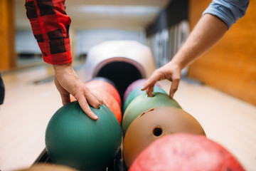 Two male bowlers takes balls from feeder - obrazy, fototapety, plakaty