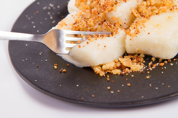 Dumplings with cottage cheese (traditional polish dish called lazy pierogi/ leniwe pierogi) fried with bread crumbs and sprinkled with sugar, eaten with a fork