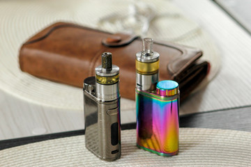 Electronic cigarette on club table in the living room.  Usually layout with electronic cigarettes and little things. Advanced model of electronic cigarette, e-cig mod or personal vaporizer.