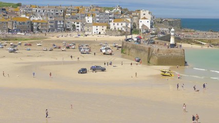Plenty of holidaymakers visiting St Ives beach, at low tide, on a gorgeous, hot day in summer, England.