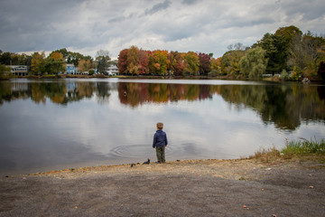 Fototapeta na wymiar toddler boy looking at pond on a beautiful autumn day