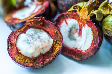 Naklejka premium Mangosteen fruit and cross section showing the thick purple skin and white flesh of the queen of fruits in China.