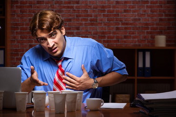 Young employee drinking coffee working at night shift 