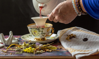 a lady's hand putting herbal tea in a cup