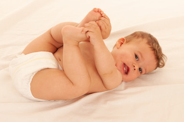 Hapy baby boy in playing on bed isolated over white