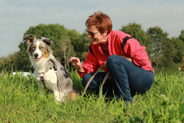 Naklejka na ściany i meble Woman with her dog in the grass