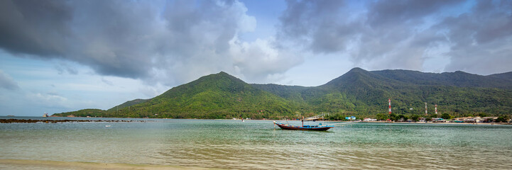Bright tropical landscape, traditional Thai fishing boat on the background of the hills on the island of Phangan Thailand