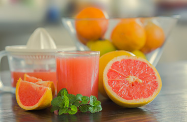 Glass of freshly squeezed grapefruit juice with juicer background.