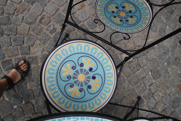 Fototapeta na wymiar A table and a chair with blue and yellow mosaic tiles in the cafe. Bucharest,Romania