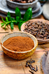 Bowls with dried clove buds and cloves powder, used for cooking and traditional medicine, close up, spices collection