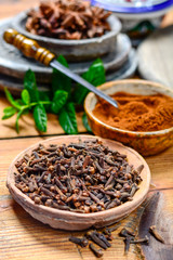 Bowls with dried clove buds and cloves powder, used for cooking and traditional medicine, close up, spices collection