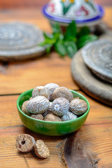 Old clay bowl with whole nutmegs close up, spices collection